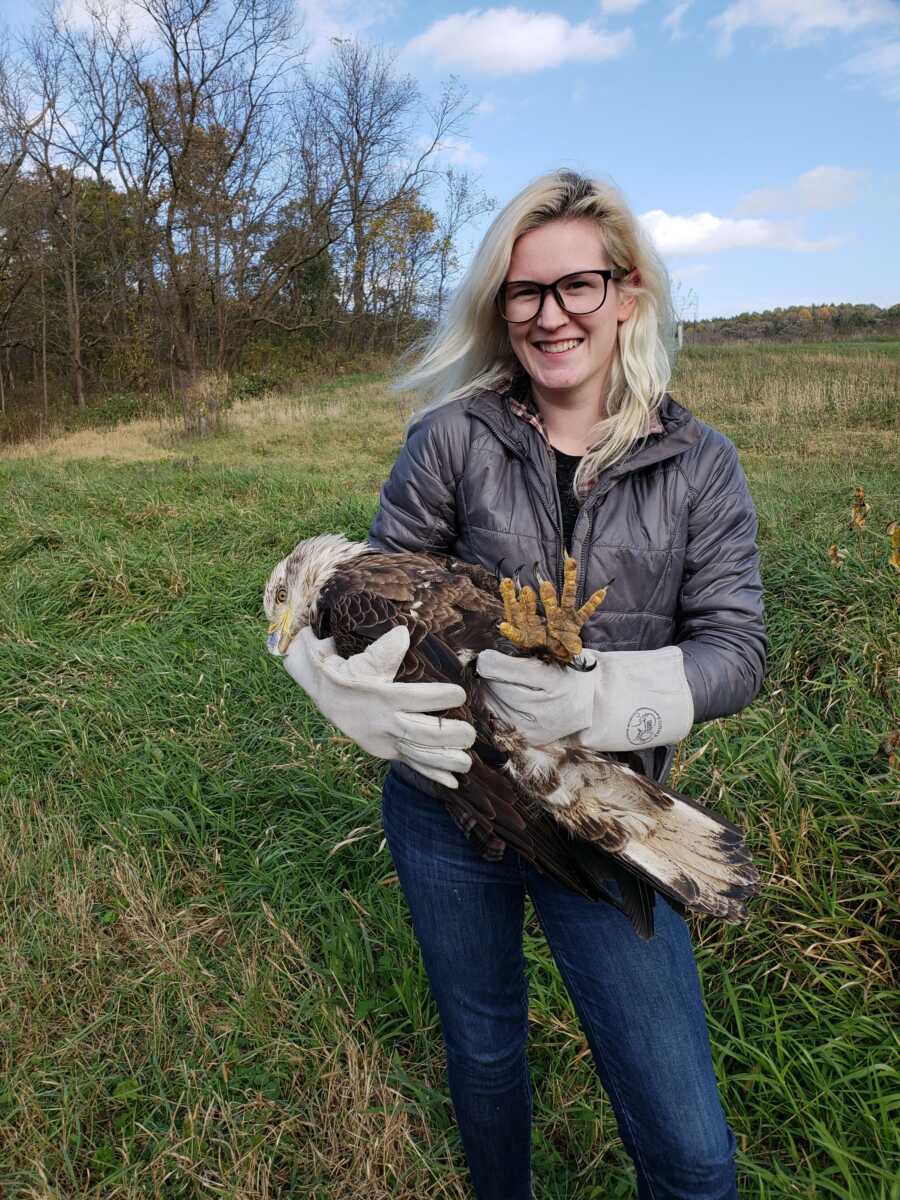 woman with a falcon in her arms smiling