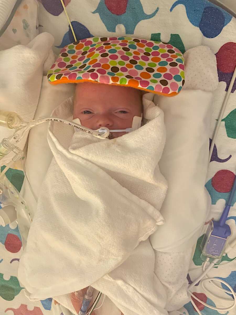 preemie baby girl wrapped up in blankets with a feeding tube