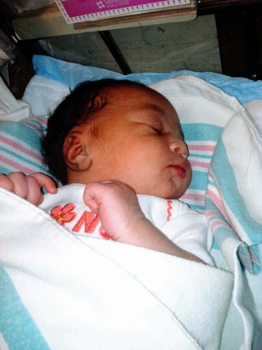 Newborn baby sleeping in hospital bed