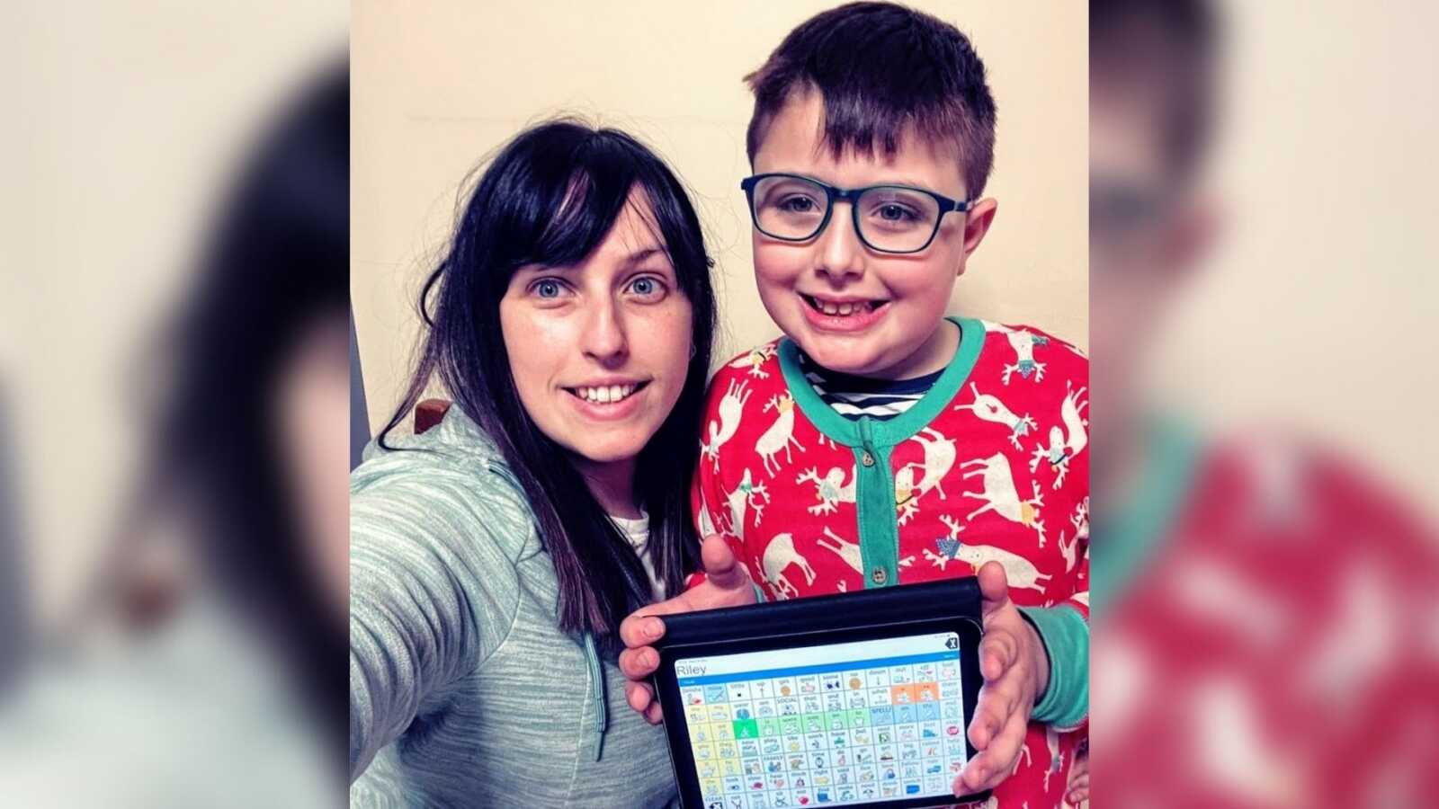 A mom and her son with autism holding a communication device