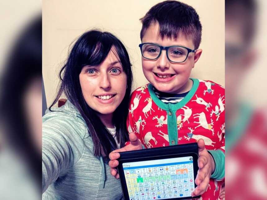 A mom and her son with autism holding a communication device