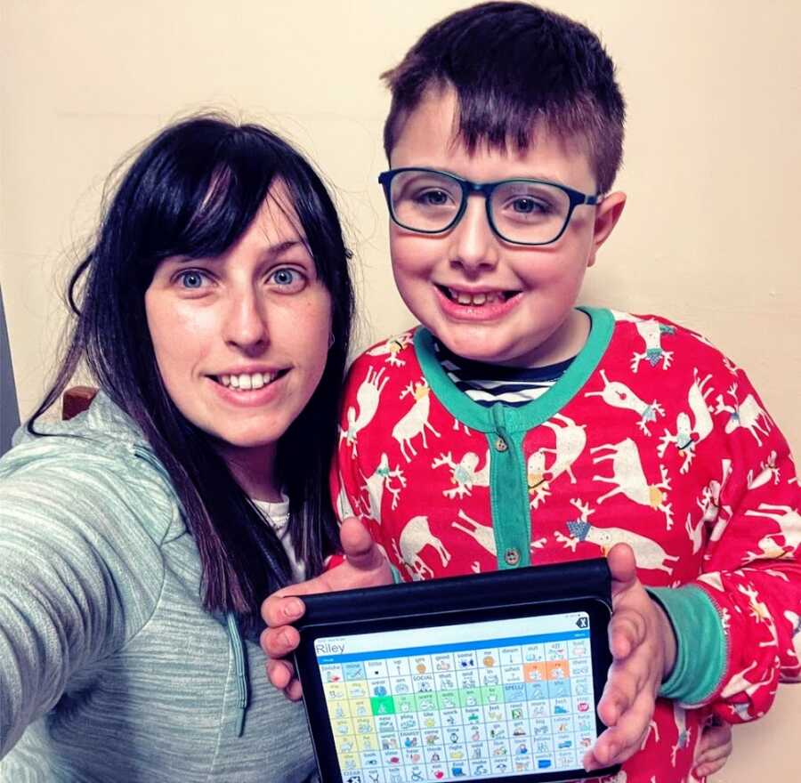 A mom and her son with autism holiding his communication device