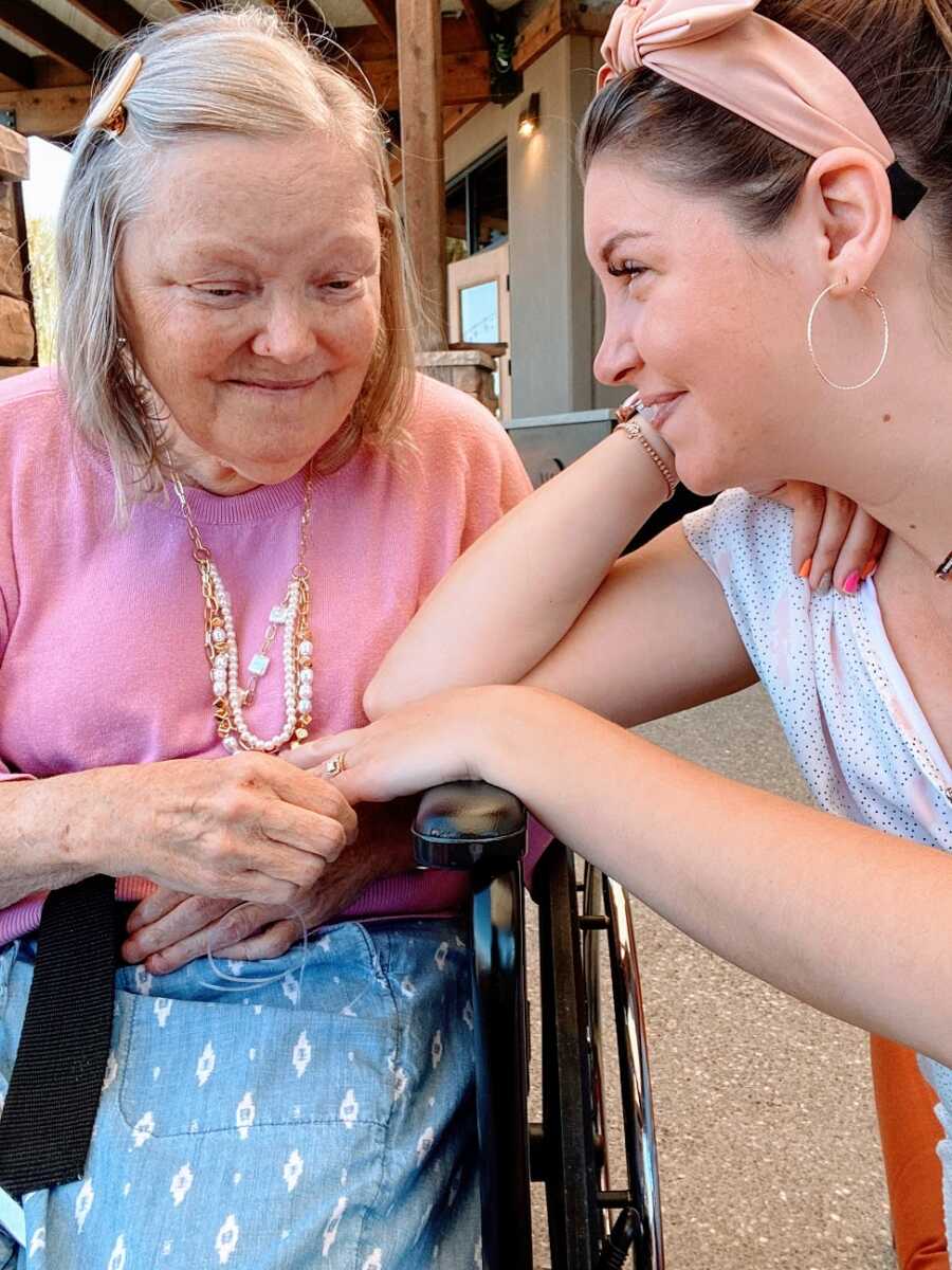 A mom sitting in a wheelchair holds her daughter's hand