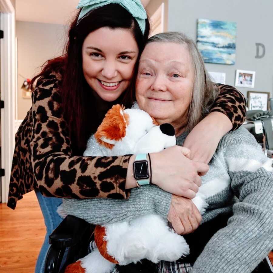 A daughter hugs her mom while holding a stuffed dog