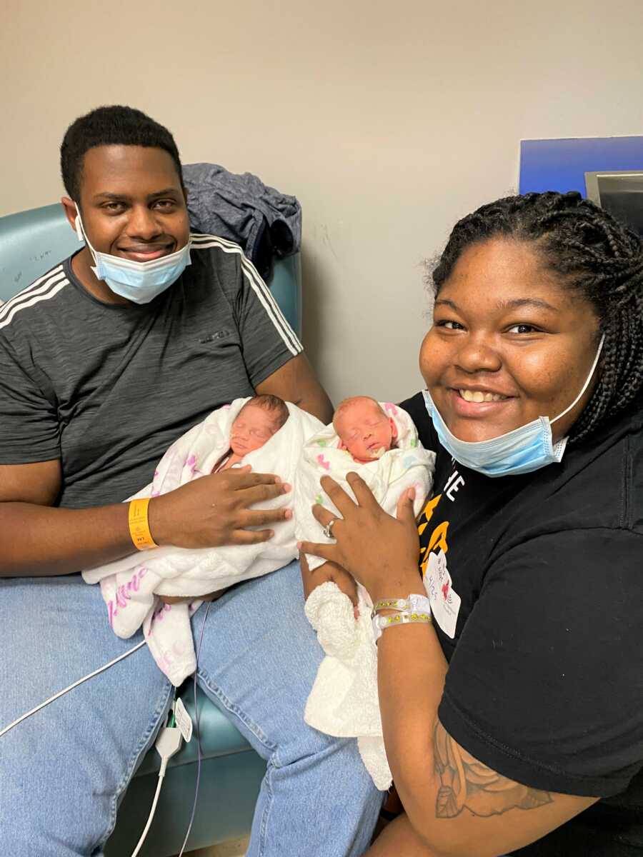 Couple holds new twin baby girls in the hospital. 