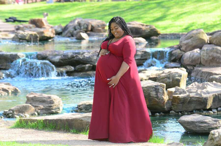 Black woman takes stunning maternity pictures in red dress.