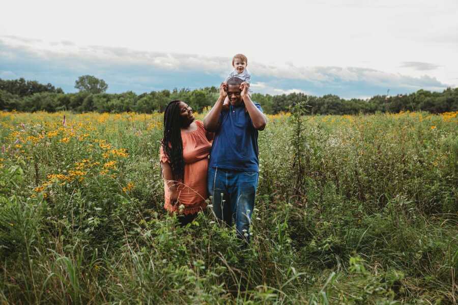 Couple takes pictures with their little boy in a field of wildflowers.