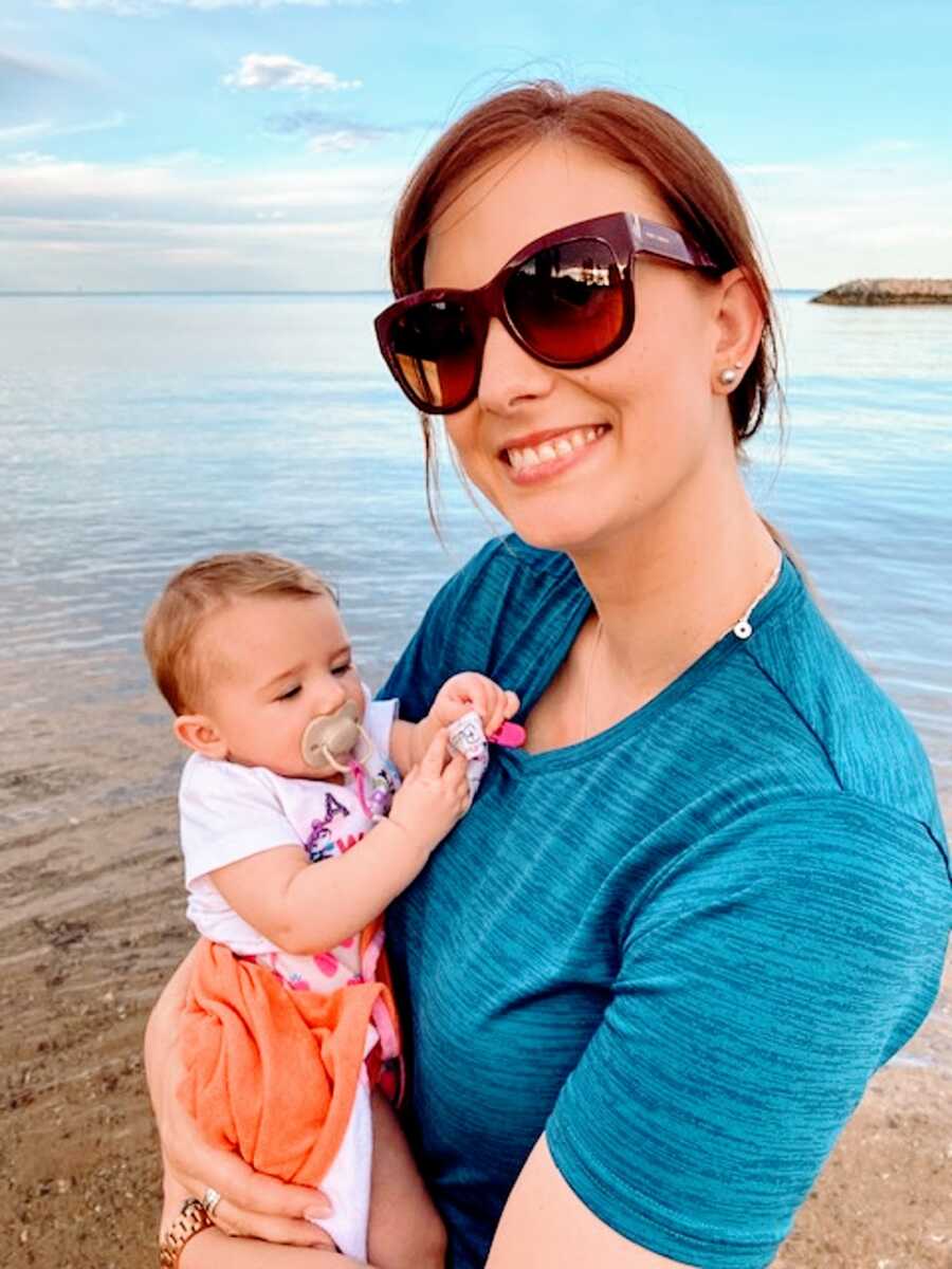 A mom holds her baby girl at the beach