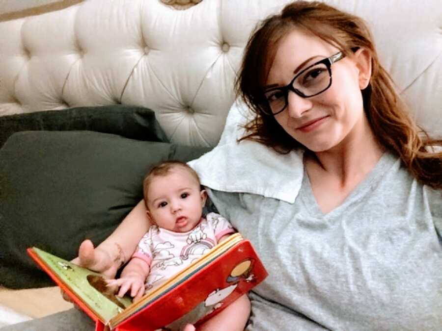 A mother holds her baby and flips through a baby book