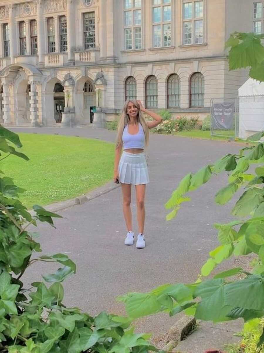 Woman confidently poses for picture in front of beautiful architecture.