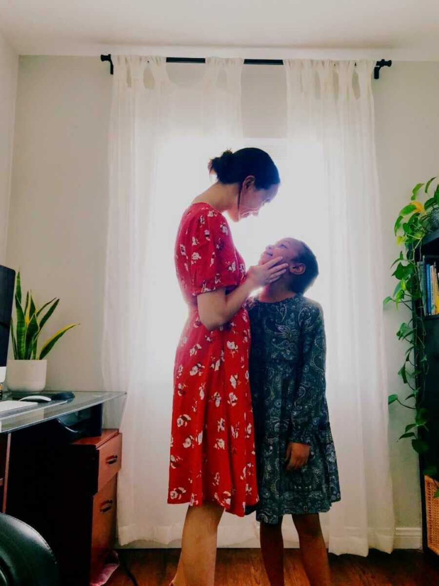 Young mom in red dress holding daughter's cheek