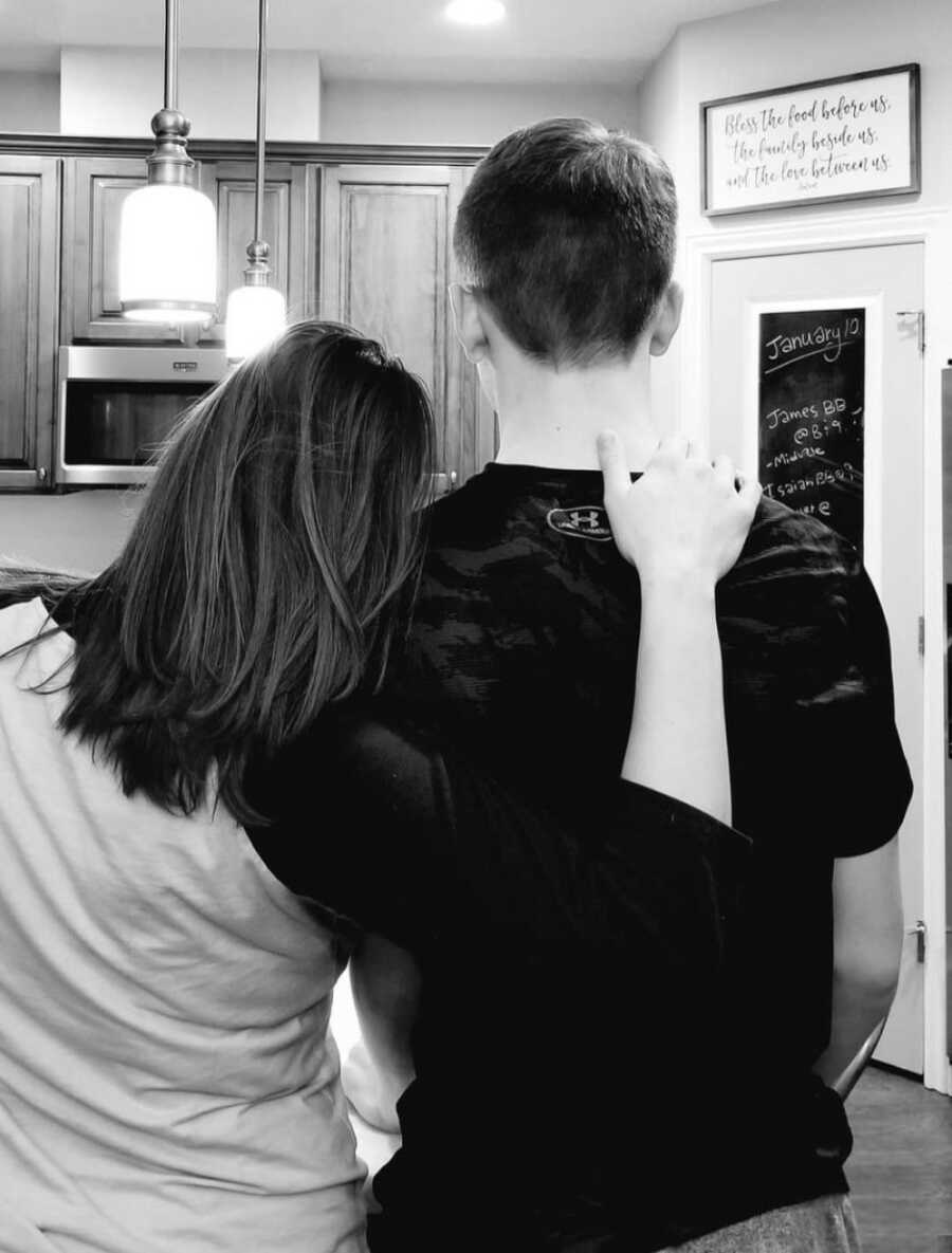 mom and son posing together with her arm around him