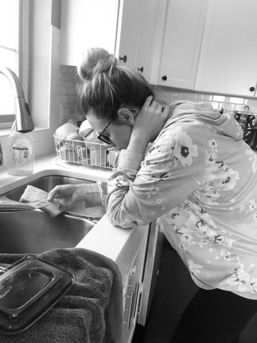 mom standing over a sink tired