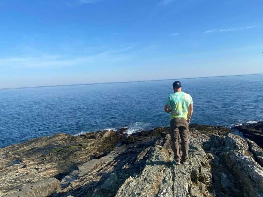man standing on a rock looking out at the ocean