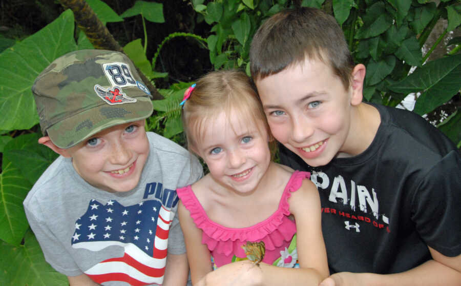 three kids smiling at mom for a picture