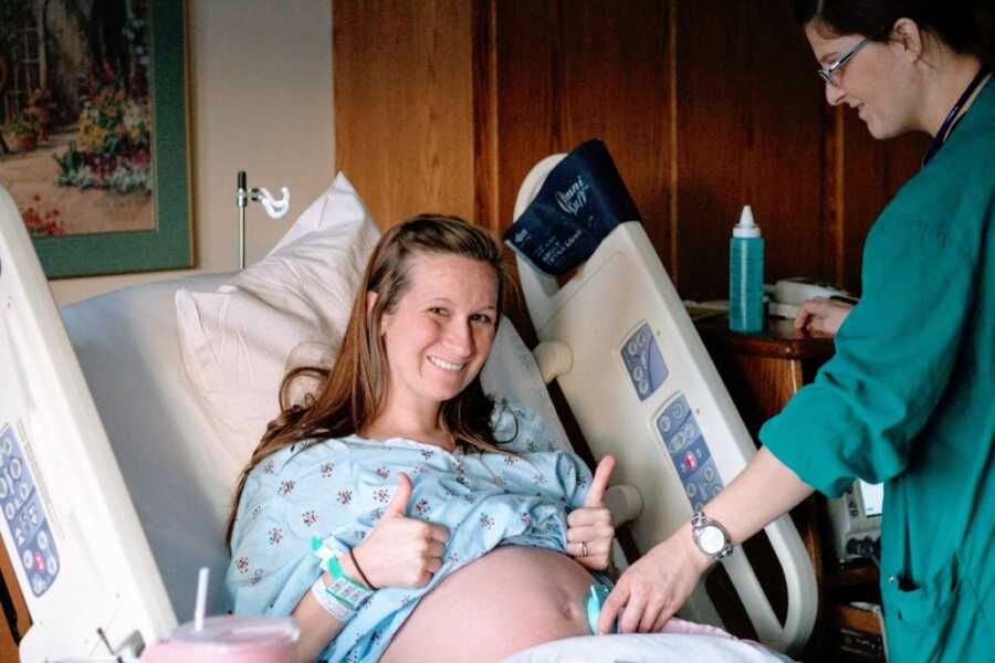 Mom pregnant with son gives the thumbs up while a nurse puts a doppler on her stomach