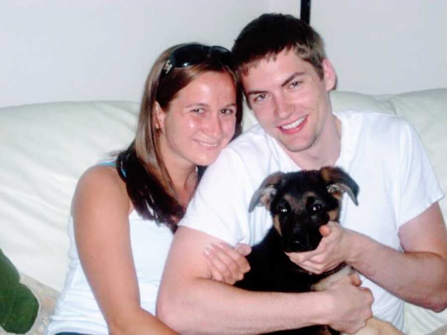 Young couple take a photo with their puppy on their couch in their new home