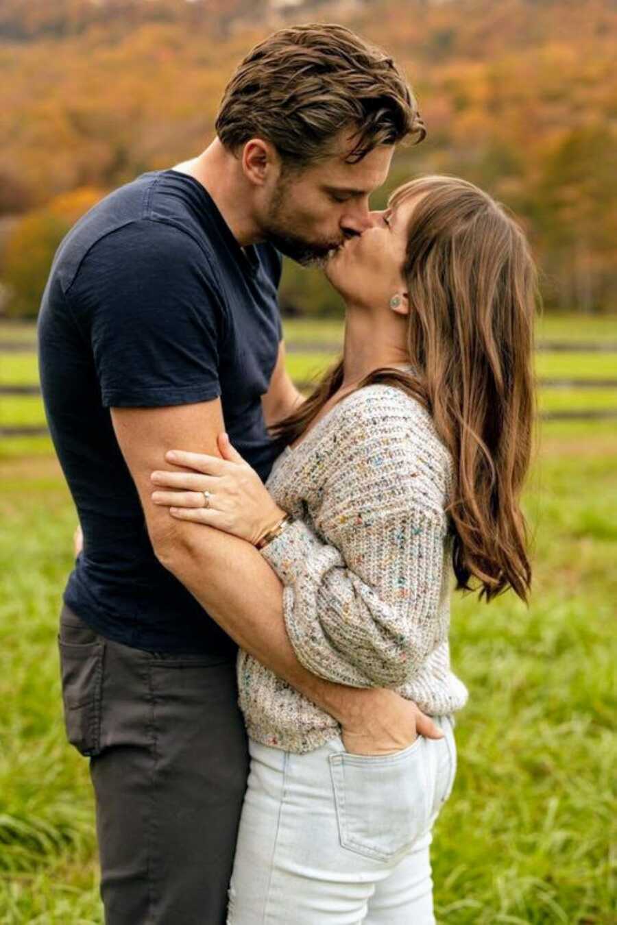 Married couple share sweet, intimate kiss during outdoor photoshoot