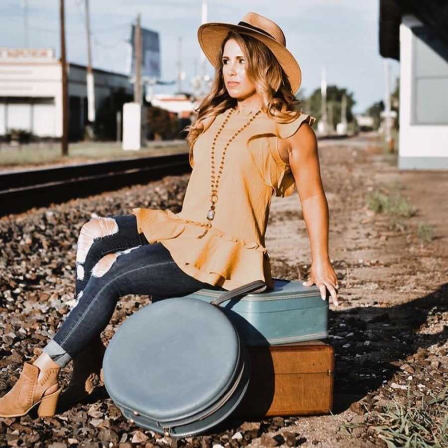 woman posing on luggage