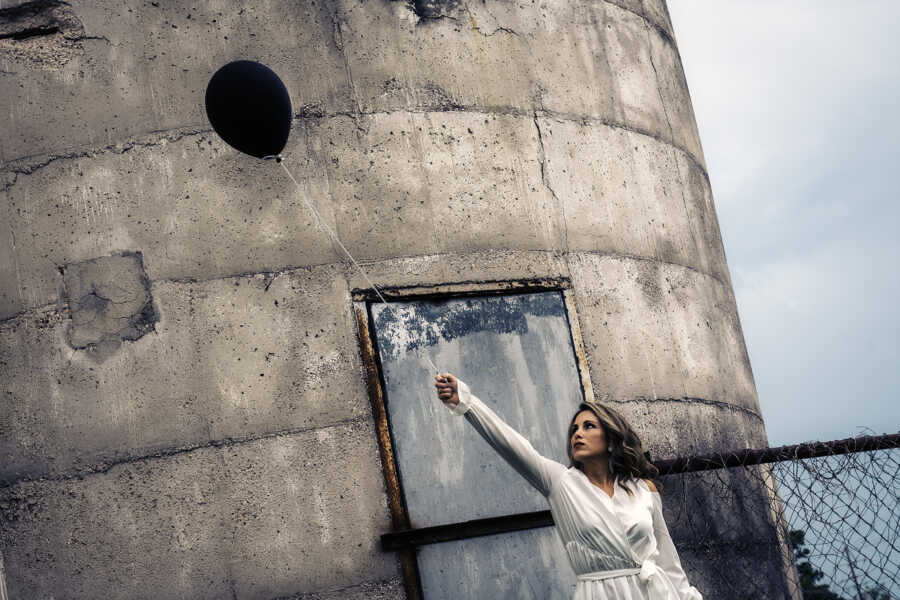 woman letting go of a black balloon