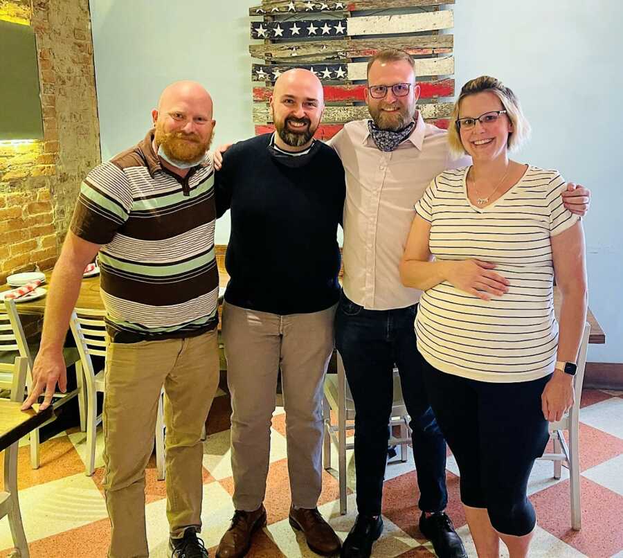 pregnant surrogate woman next to husband and gay parents to be