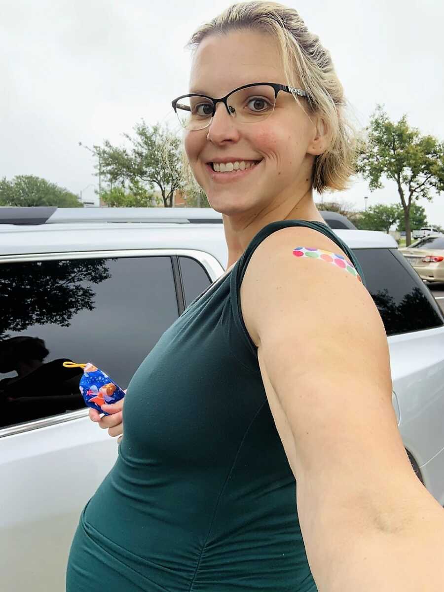 pregnant surrogate woman walking to her car, with a colorful band aid on her arm