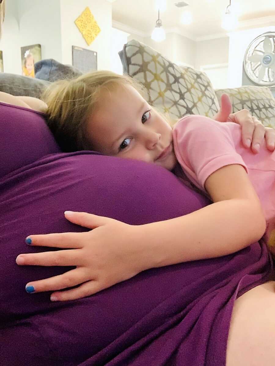 daughter holding the belly of her pregnant surrogate mom 