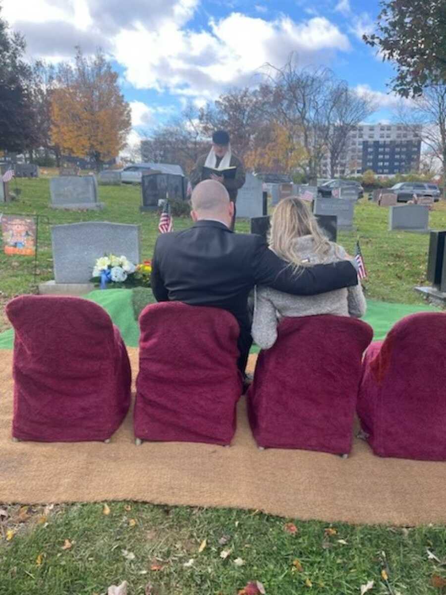 father and mother sitting at the funeral of their children