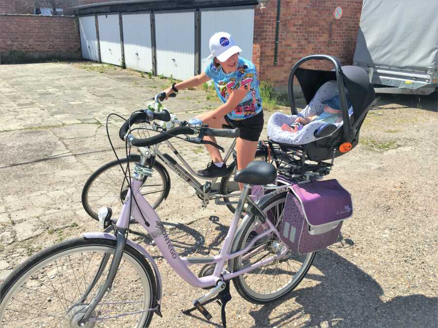 sister looking at baby brother while while on a bike 