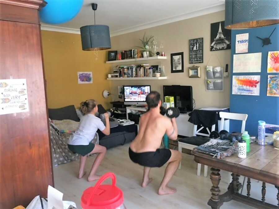 Dad and daughter exercising with dumbbells at home 