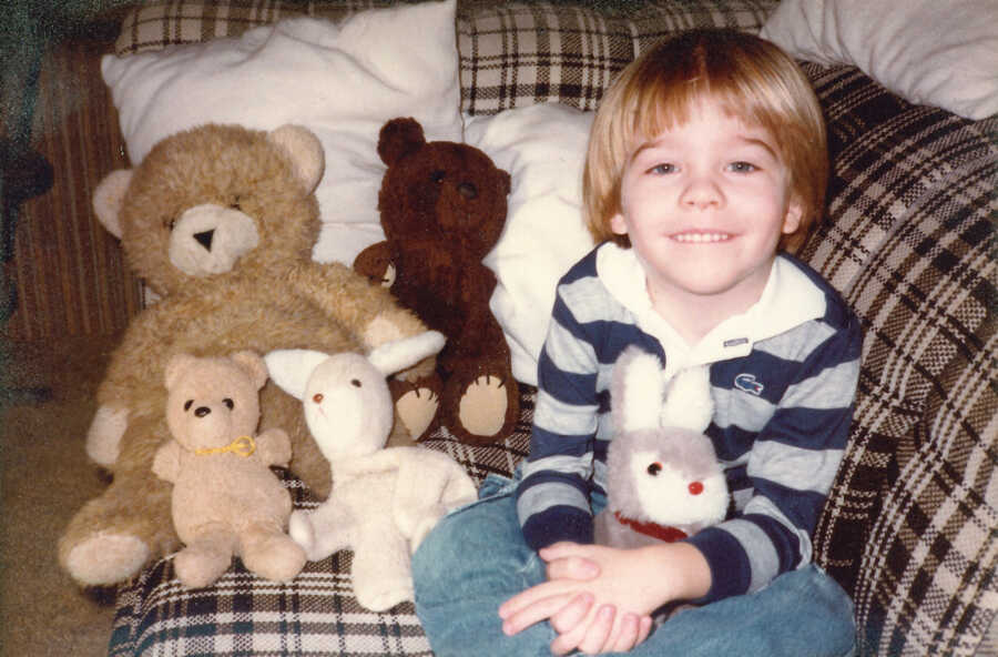 little boy surrounded by his stuffed animals