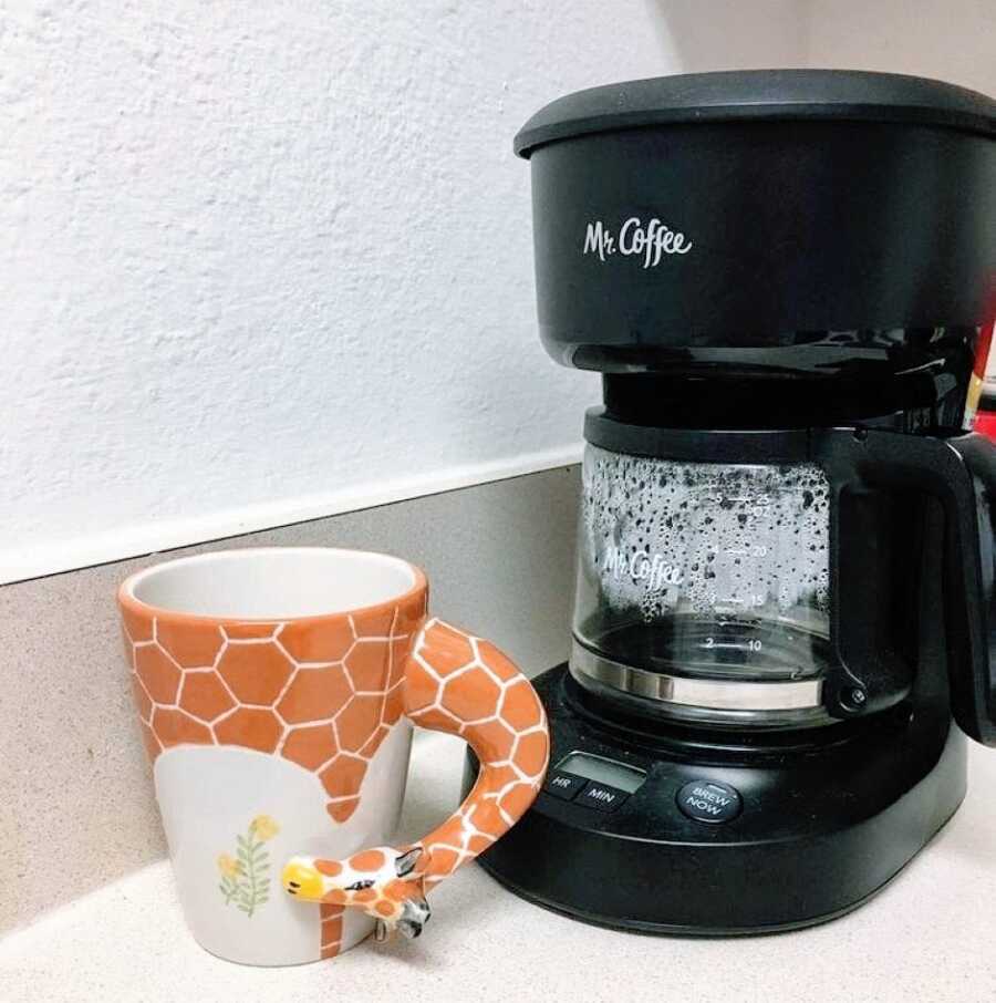 Motherless daughter takes a photo of a Mr. Coffee coffeepot with a giraffe mug next to it