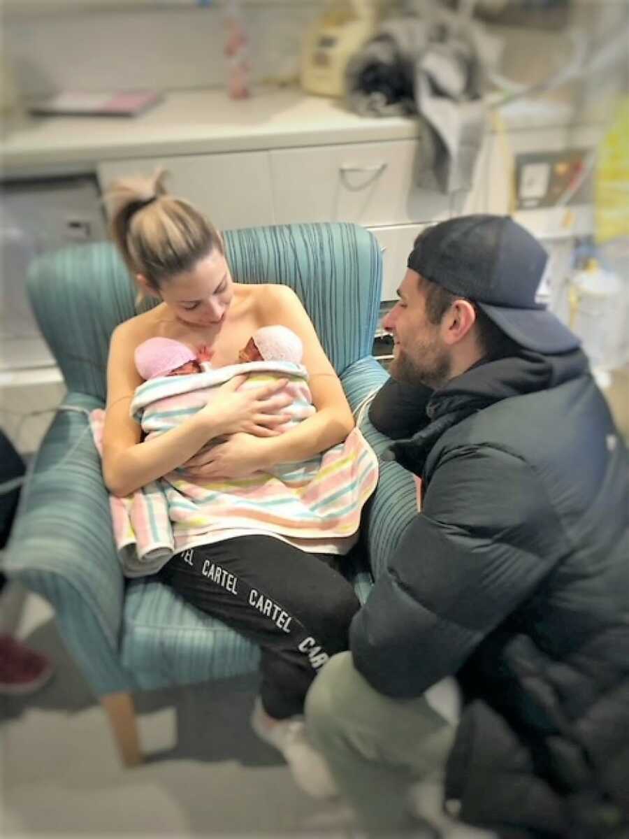 Mom holding TTTS preemies on her chest at NICU while dad admires them 