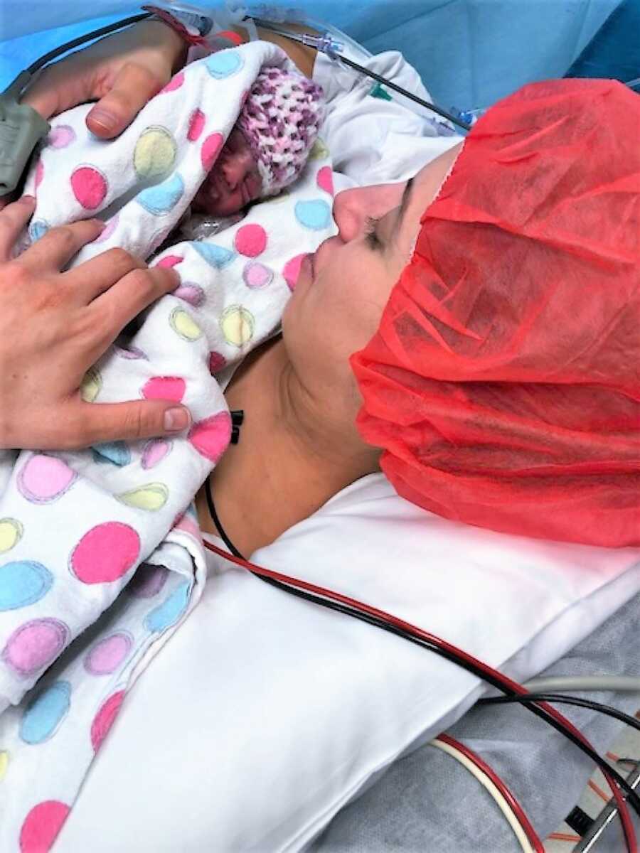 Mom holding one of her twin preemies after emergency C-section 