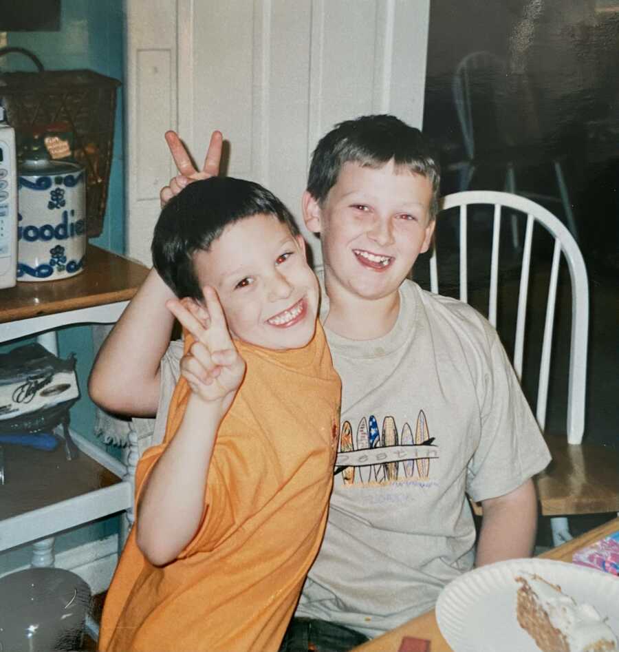 brothers at a table doing bunny ears