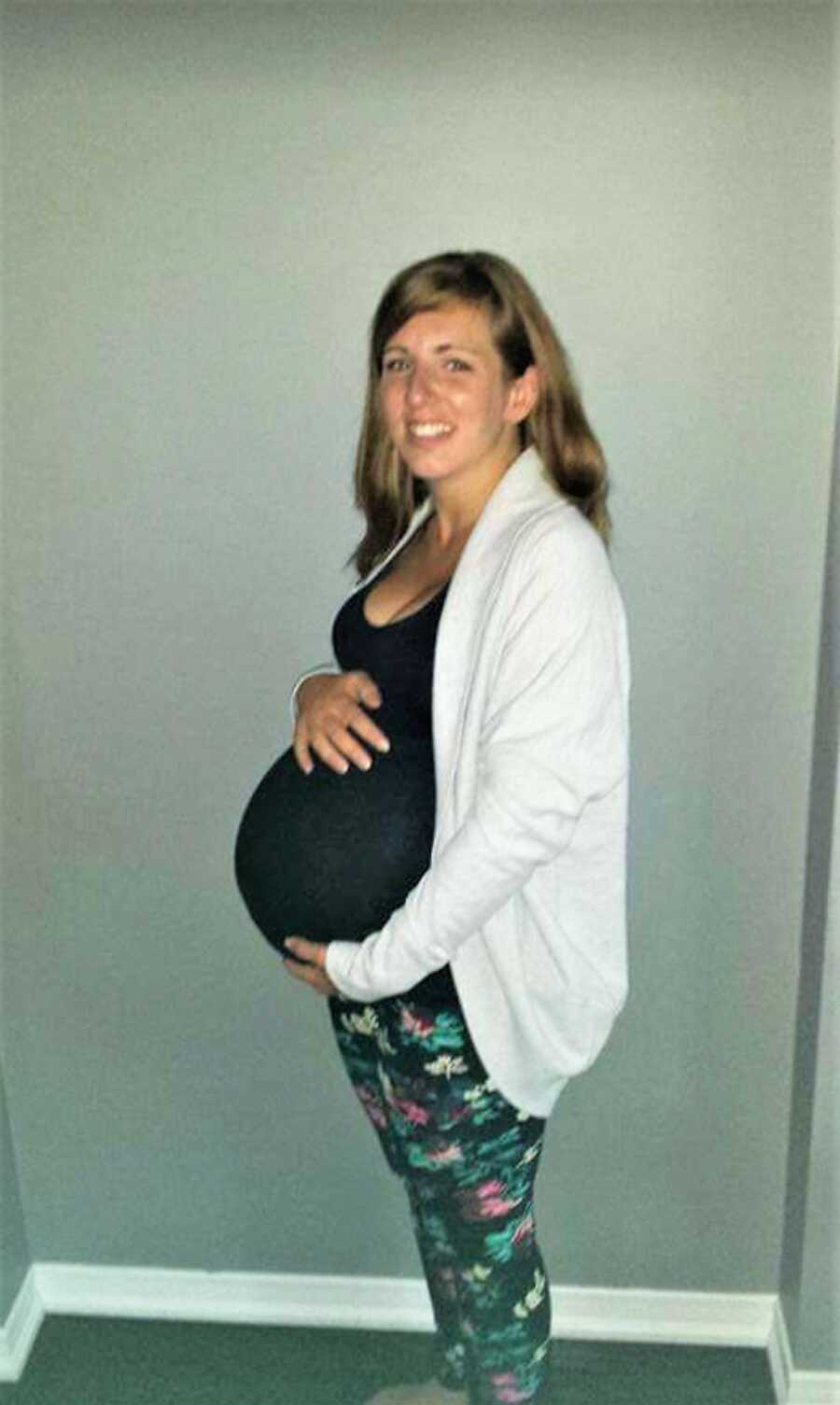 pregnant woman holds big belly with both hands