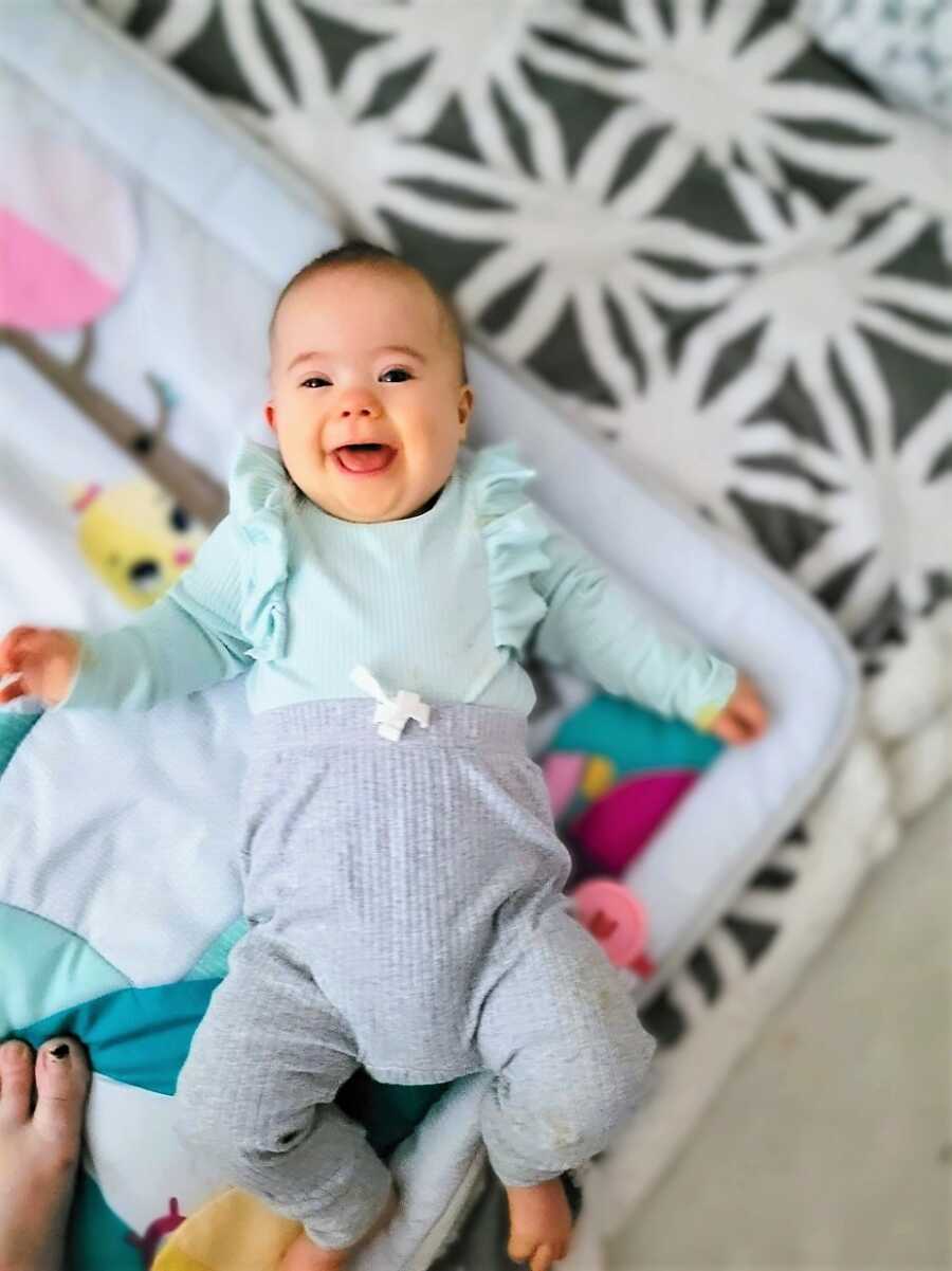 Mom takes photo of her daughter with Down Syndrome on a play mat on the floor