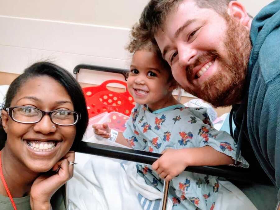 Medically complex child takes a selfie with her parents from a hospital bed