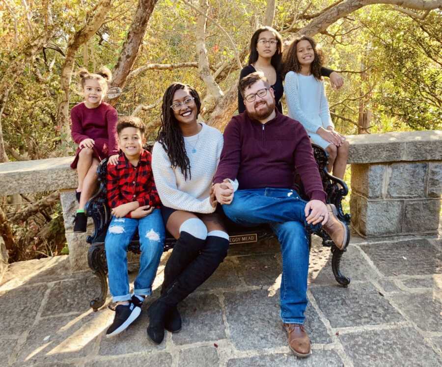 Family of six take a fall-themed group photo together on a park bench