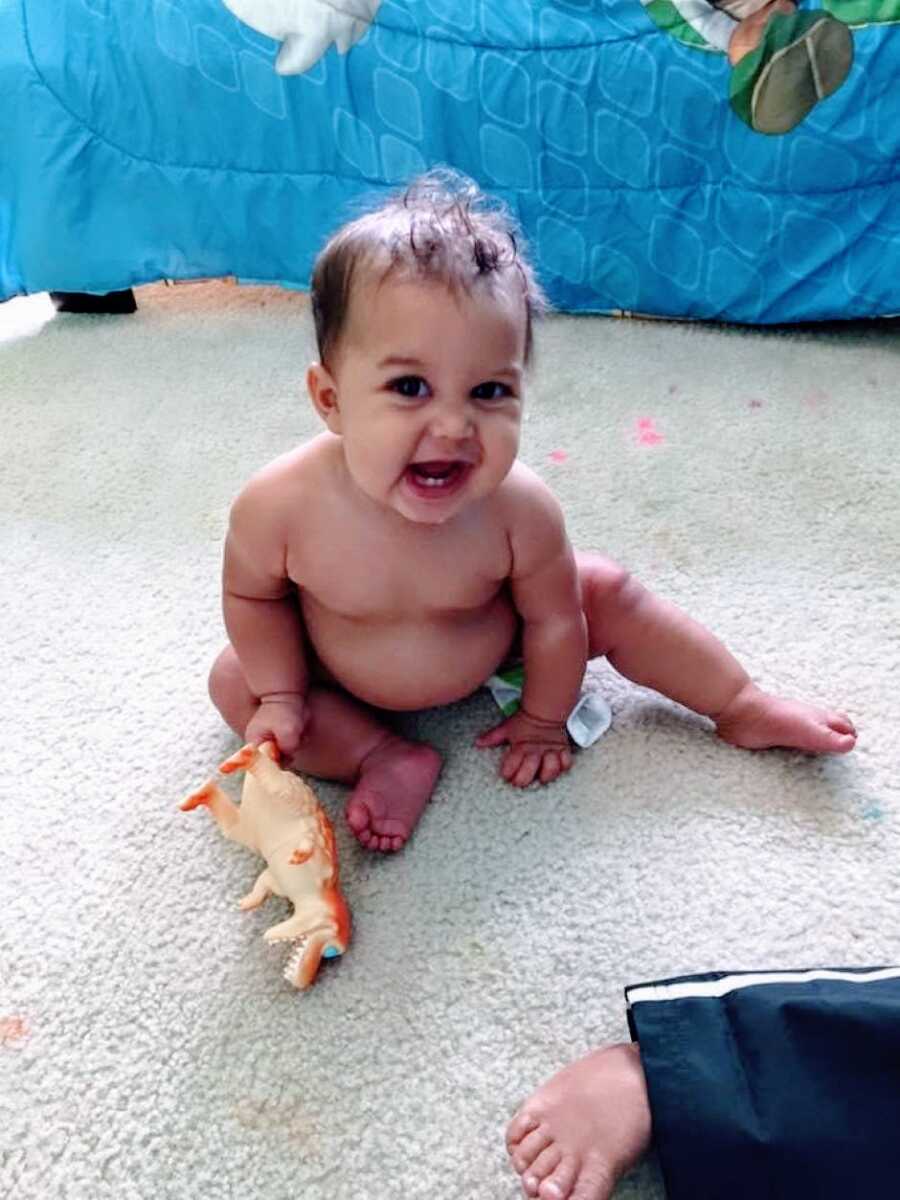 Young daughter having troubles eating smiles and plays on the floor