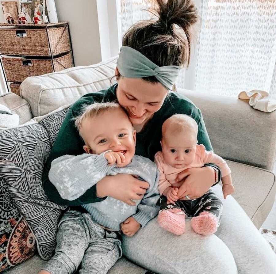 Mom smiles down to her kids while they sit on the couch together