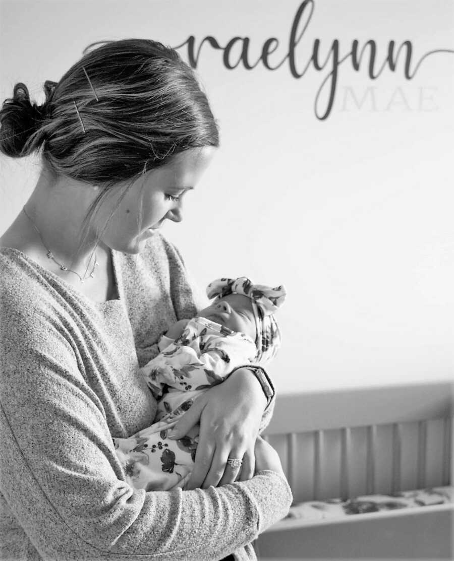 Mom holding newborn daughter in her arms while staring at her 