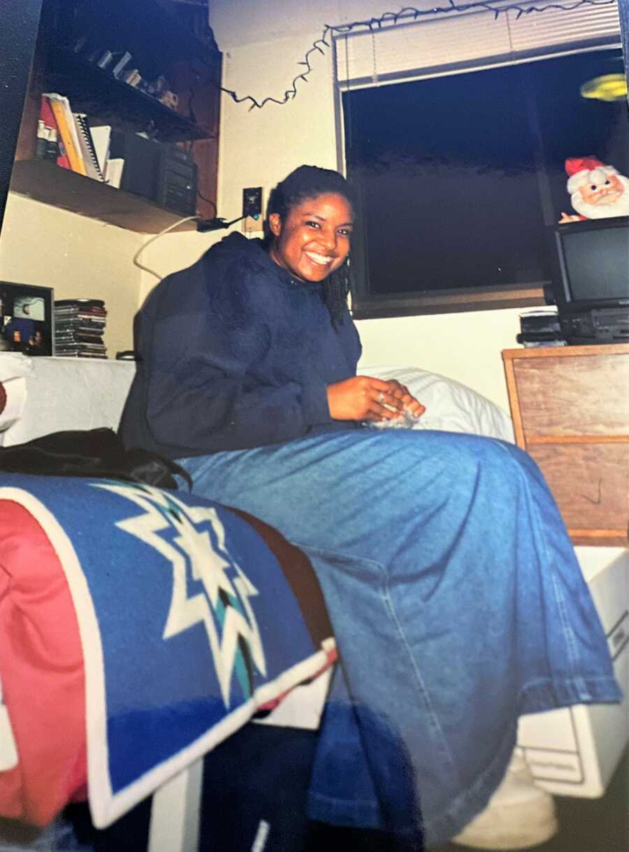 African American college student sitting in her bed at her college dorm
