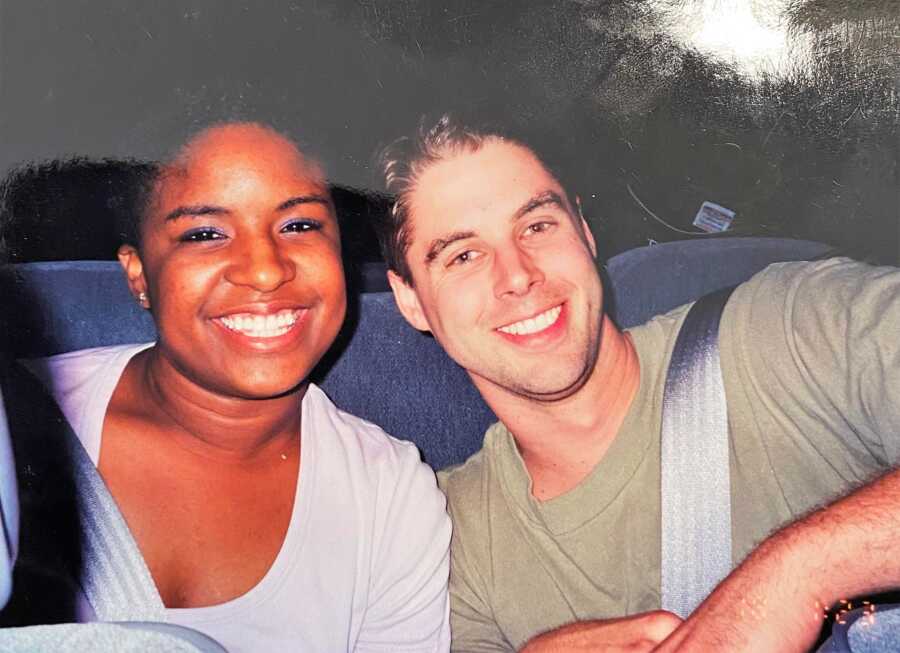 young Interracial couple sitting in a bus and smiling 