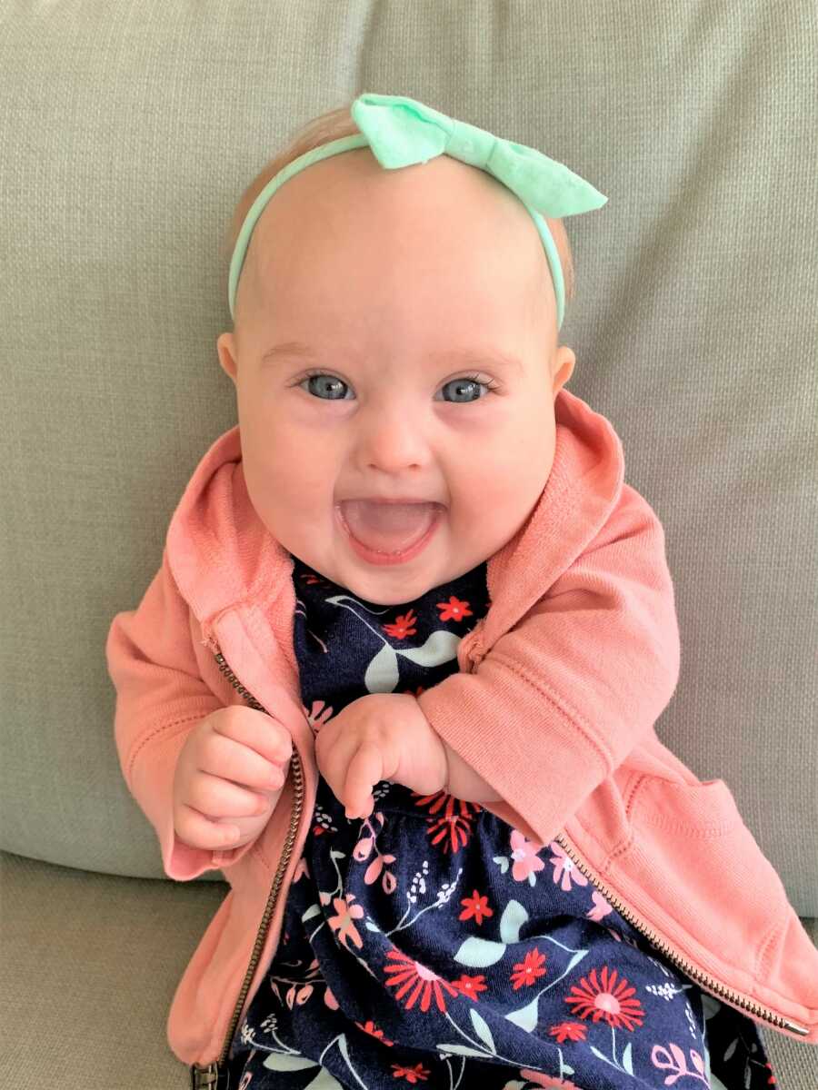 Baby girl with Down Syndrome smiling big 