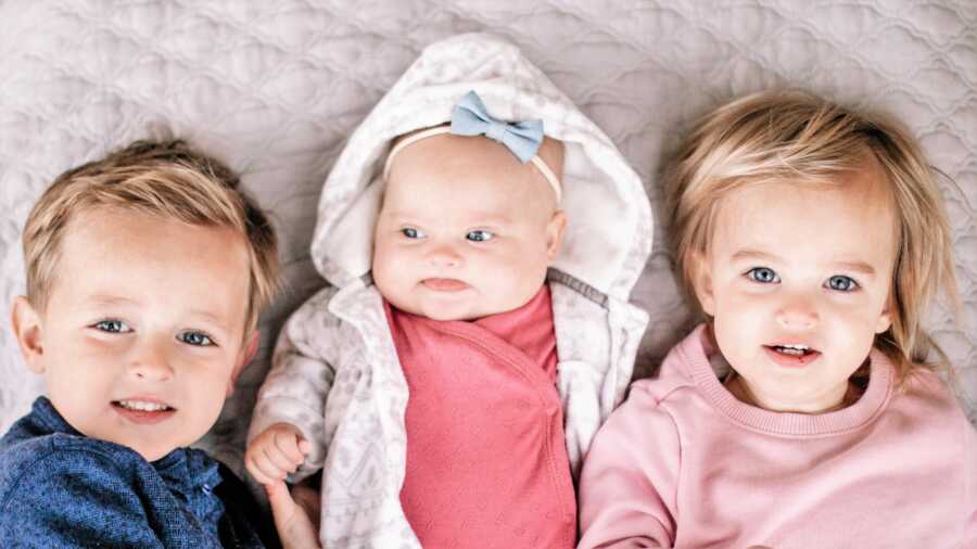 Down Syndrome baby girl laying in between her two baby siblings