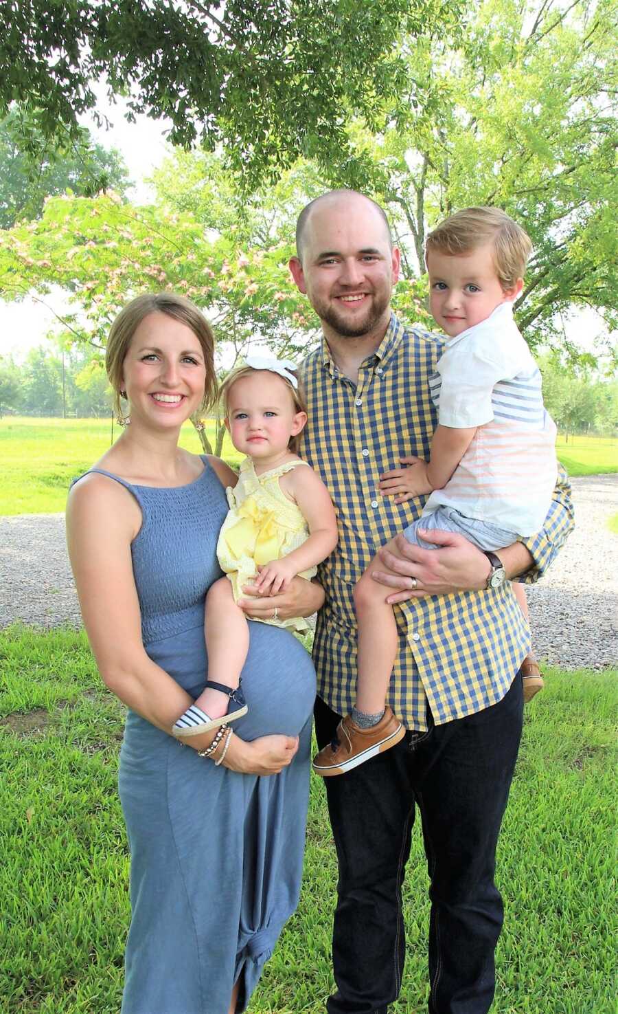 family portrait of pregnant mom holding baby daughter next to dad holding son