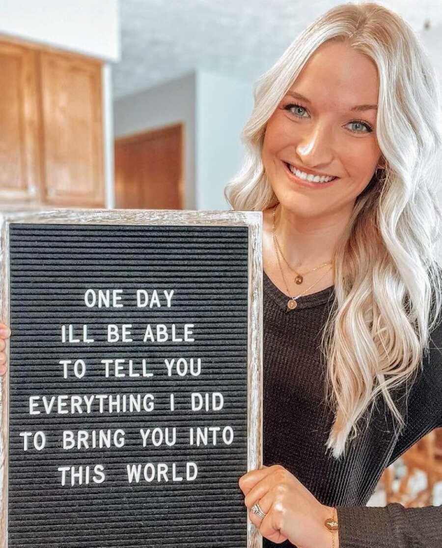 Woman struggling with infertility hopes a sign that reads 'One day I'll be able to tell you everything I did to bring you into this world'