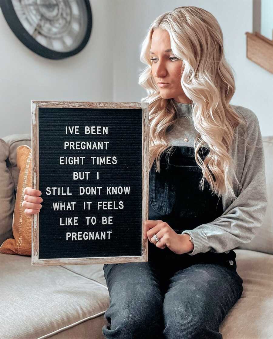 Woman battling infertility holding a sign talking about 8 pregnancy losses