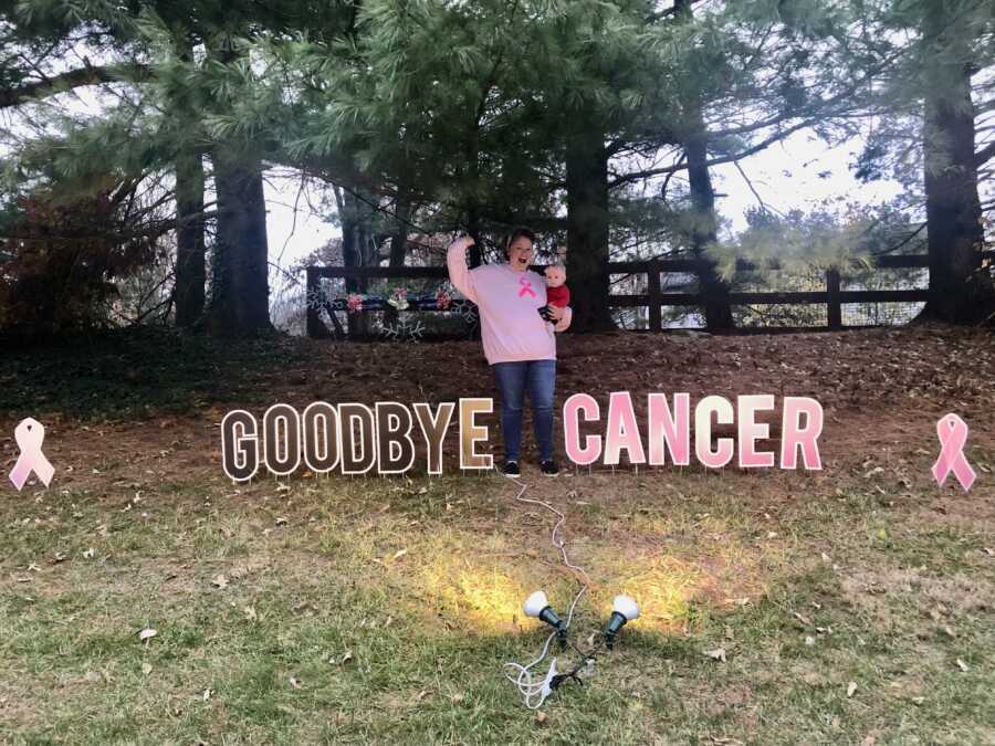 woman taking picture with a sign after beating cancer